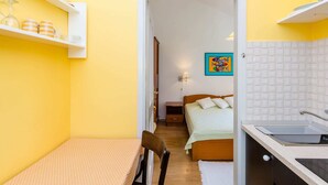 A compact kitchen with a sink and a small dining area with a table and chair. - Apartments Lion - One Bedroom Apartment (Dubrovnik)