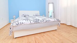 A bedroom with a bed, a nightstand, a mirror, and a window with curtains. - Apartment Marjana Prizba - Two Bedroom Apartment With Terrace and Partial Sea View (Blato)