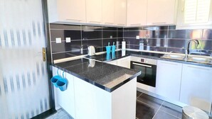 A modern kitchen with white cabinets, black countertops, and stainless steel appliances. - Apartment Marjana Prizba - Two Bedroom Apartment With Terrace and Partial Sea View (Blato)