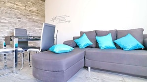 A modern living room with a grey sectional sofa, a glass coffee table, and a stone wall. - Apartment Marjana Prizba - Two Bedroom Apartment With Terrace and Partial Sea View (Blato)