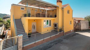 A two-story yellow building with a balcony, a fireplace, and a staircase. - Fancy Apartments Dream - Comfort One Bedroom Apartment With Balcony and Sea View (Smokvica)