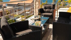 A balcony with wicker furniture, a glass table, and a bottle of wine. - Fancy Apartments Dream - Comfort One Bedroom Apartment With Balcony and Sea View (Smokvica)
