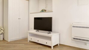 A room with a white wardrobe, a TV on a white stand, and an air conditioner. - Apartment City Gem - Studio (Dubrovnik)