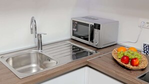 A kitchen with a stainless steel sink, a microwave, and a basket of fruit on the counter. - Apartment City Gem - Studio (Dubrovnik)