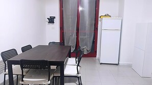 A dining area with a table and chairs, a refrigerator, and a door with curtains. - Holiday Home Near Marina di Mandatoriccio Beach (Mandatoriccio)
