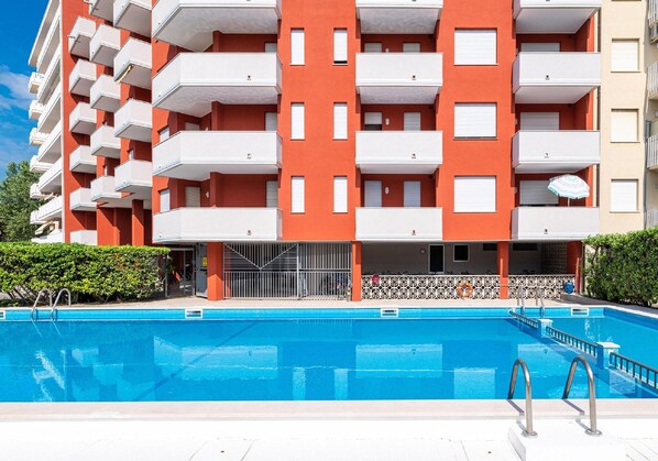 A multi-story building with balconies and a swimming pool in front. - Holiday Home in Caorle Near Spiaggia Tartaruga (Caorle)
