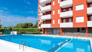 A swimming pool adjacent to a multi-story building with balconies. - Holiday Home in Caorle Near Spiaggia Tartaruga (Caorle)