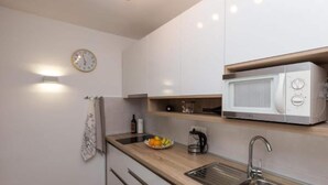 Eine moderne Küche mit weißen Schränken, einer Edelstahl-Spüle, einer Mikrowelle und einer Holz Arbeitsplatte.