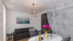 Ein modernes Wohnzimmer mit einem grauen Sofa, einem kleinen Tisch mit Blumenvase und einem Bild an der Wand.