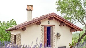 A small, rustic building with a tiled roof, a chimney, and a door with a blue frame. - Belvilla by OYO Bilocale Monolocale 2adeg Piano (Assisi)