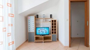 Huone, jossa on sisäänrakennettu televisio, puuhyllyt ja pistorasia.