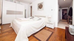 A modern bedroom with a bed, bedside tables, a wardrobe, and a framed picture on the wall. - Apartment Vesna - Superior Three Bedroom Apartment With Balcony (Dubrovnik)