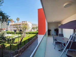A balcony with a table and chairs, overlooking a well-maintained garden and buildings in the background. - Apartment Vesna - Superior Three Bedroom Apartment With Balcony (Dubrovnik)