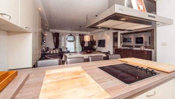A modern kitchen with a central island, built-in oven, and a dining area with a table and chairs. - Apartment Vesna - Superior Three Bedroom Apartment With Balcony (Dubrovnik)