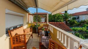 A balcony with wooden furniture, a table, and a covered area. - Apartments Roda - One Bedroom Apartment With Terrace - (Supetar)