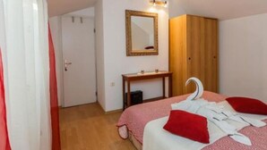 A bedroom with a bed, a wooden wardrobe, a mirror, and a small table. - Apartments Roda - One Bedroom Apartment With Terrace - (Supetar)