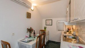 A compact kitchen with a dining table, chairs, a small refrigerator, and a sink. - Apartments Roda - One Bedroom Apartment With Terrace - (Supetar)