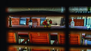 A cozy room with a bed, a table with a vase of flowers, and a bottle of liquor.