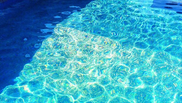 A clear view of a swimming pool with visible water patterns and a pool edge.