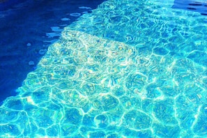 A clear view of a swimming pool with visible water patterns and a pool edge.