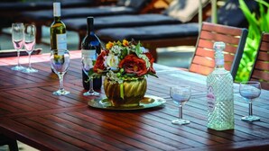 A wooden table with a vase of flowers, wine bottles, and glasses.