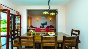 A dining area with a wooden table and chairs, a vase with flowers, and a bowl of oranges.