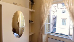 A room with a large window, a radiator, and a mirror.