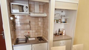 A compact kitchen with a microwave, stove, sink, and storage cabinets.