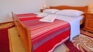 Una cama bien hecha con una colcha a rayas rojas, almohadas blancas y un cabecero de madera.