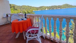 Un balcón con mesa y sillas que ofrece vistas panorámicas de la costa.
