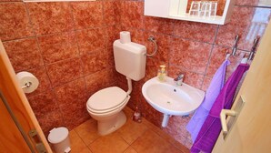 Un baño con inodoro, lavamanos y espejo sobre el lavamanos.