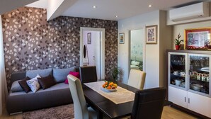 Una sala de estar moderna con un sofá, una mesa de comedor y un mueble con puertas de vidrio.