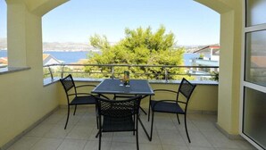 A balcony with a table and chairs, a view of the sea, and a building in the background. - Apartments Villa Moonlight - One Bedroom Apartment With Sea View Balcony (Okrug)