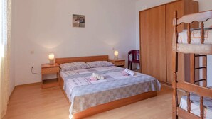 A bedroom with a wooden bed, two bedside tables with lamps, a wooden wardrobe, and a red chair. - Seafront Apartments Olivera-one Bedroom Apartment With Balcony and Sea View (Blato)