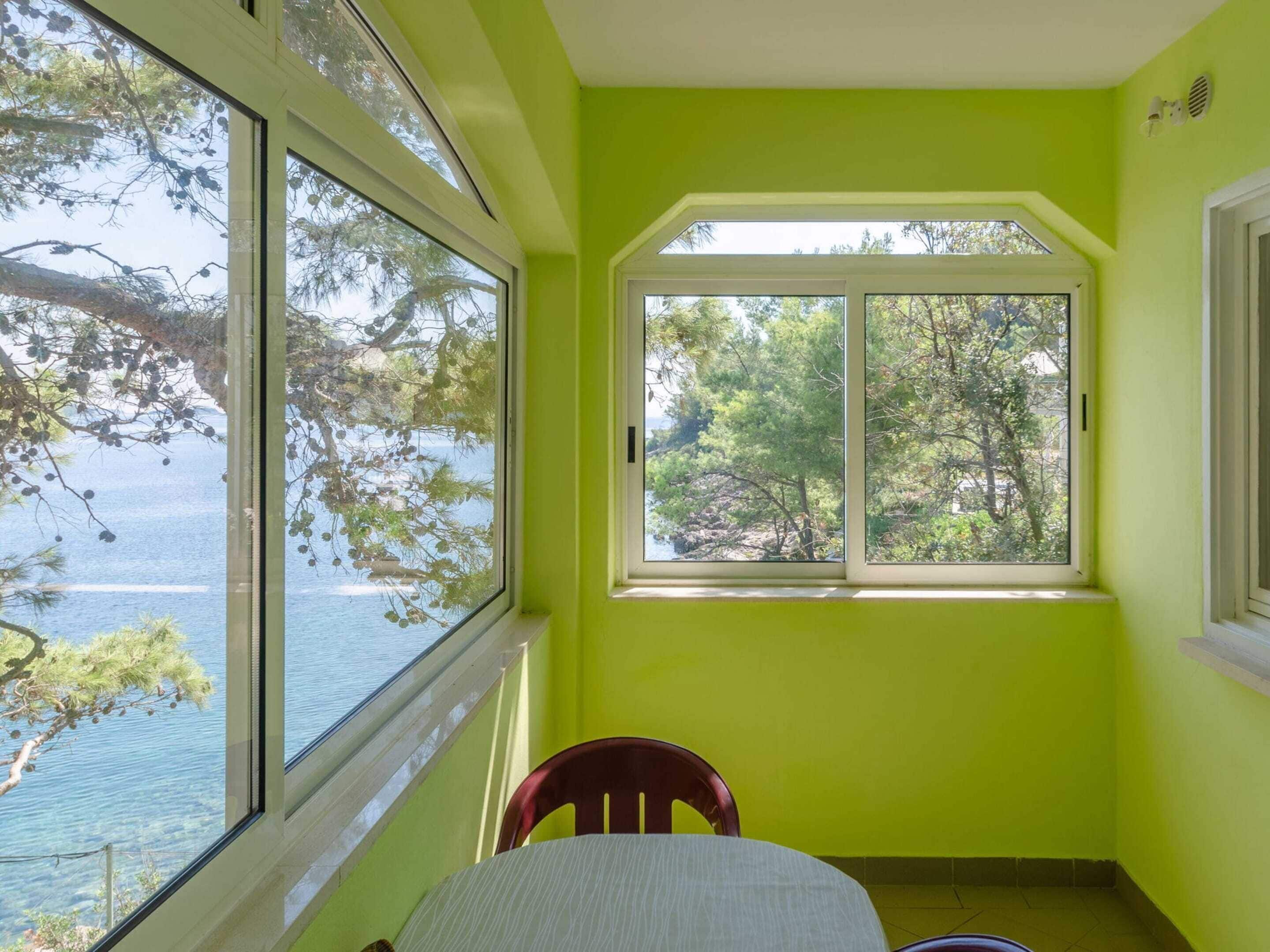 A room with a large bay window overlooking a body of water and trees.