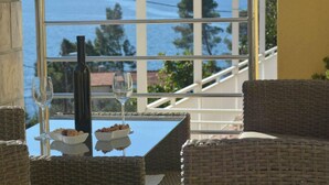 A balcony with wicker furniture, a glass table, a bottle, and two wine glasses. - Fancy Apartments Dream - Deluxe One Bedroom Apartment With Balcony and Sea View (Smokvica)