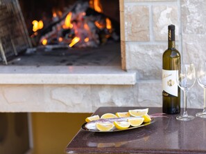 A fireplace with a bottle of wine and glasses on a table.