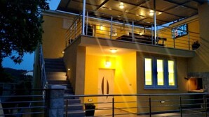 Ein modernes, zweistöckiges Haus mit Balkon, Treppe und Tür.