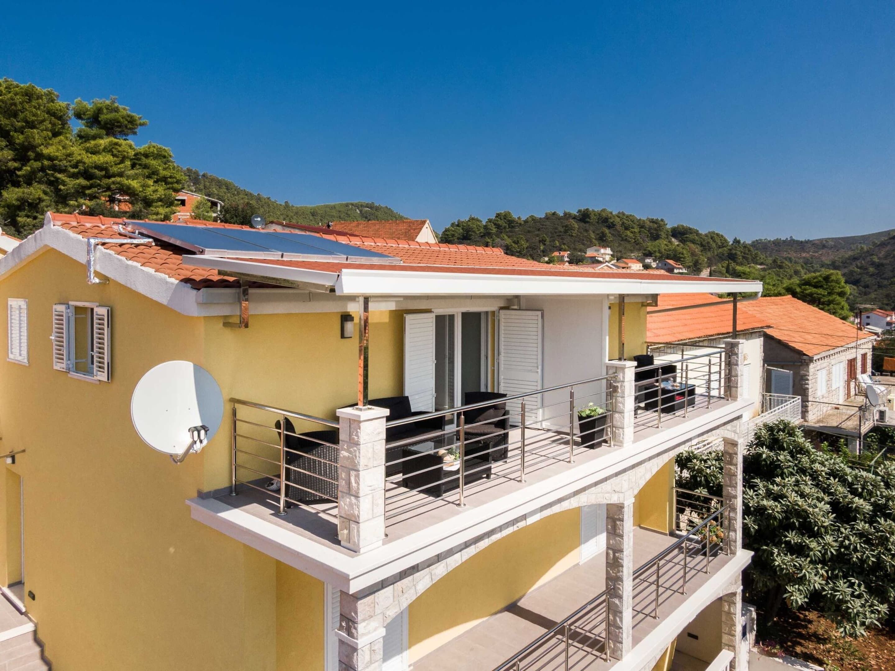Un edificio amarillo con balcón, paneles solares y antena parabólica.