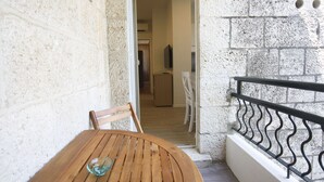 A wooden table with a glass bowl, a white chair, and a stone wall. - Apartment Goge - One-bedroom Apartment With Balcony (Dubrovnik)