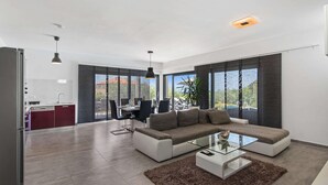A modern living room with a sectional sofa, a glass coffee table, and a dining area with chairs and a table. - Modern Villa With Pool, Covered Terrace and sea View (Novigrad)