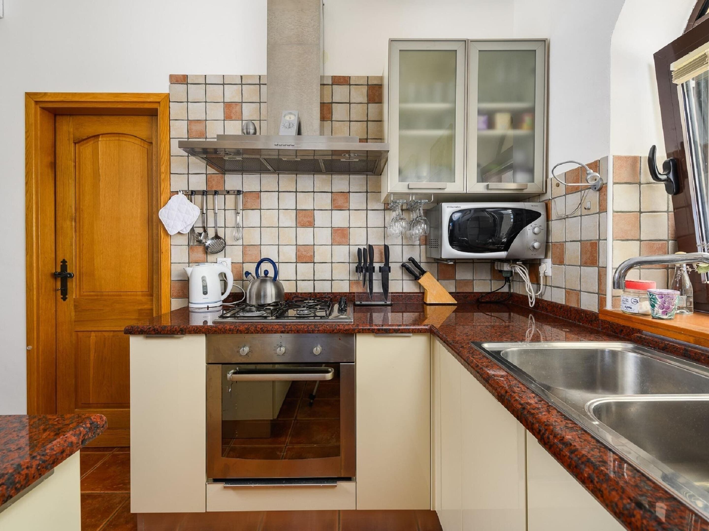 A compact kitchen with a stove, oven, microwave, and a sink.