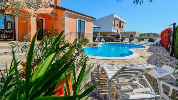 A pool area with lounge chairs, a barbecue, and a building with a brick facade. - Spacious Holiday Home in Visnjan With Private Pool (Visnjan)