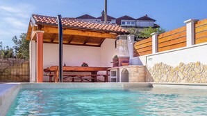 A swimming pool with a stone wall and a wooden deck. - Apartment in Liznjan With Pool and Terrace (Liznjan)