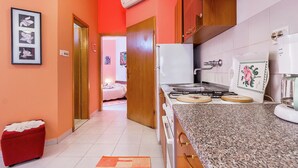 A kitchen with a gas stove, white cabinets, and a red wall. - Apartment in Liznjan With Pool and Terrace (Liznjan)