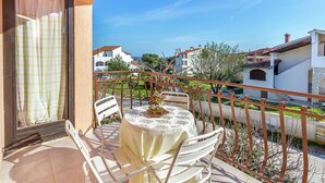 A balcony with a table and chairs, overlooking a residential area with houses and a clear sky. - Apartment in Liznjan With Pool and Terrace (Liznjan)