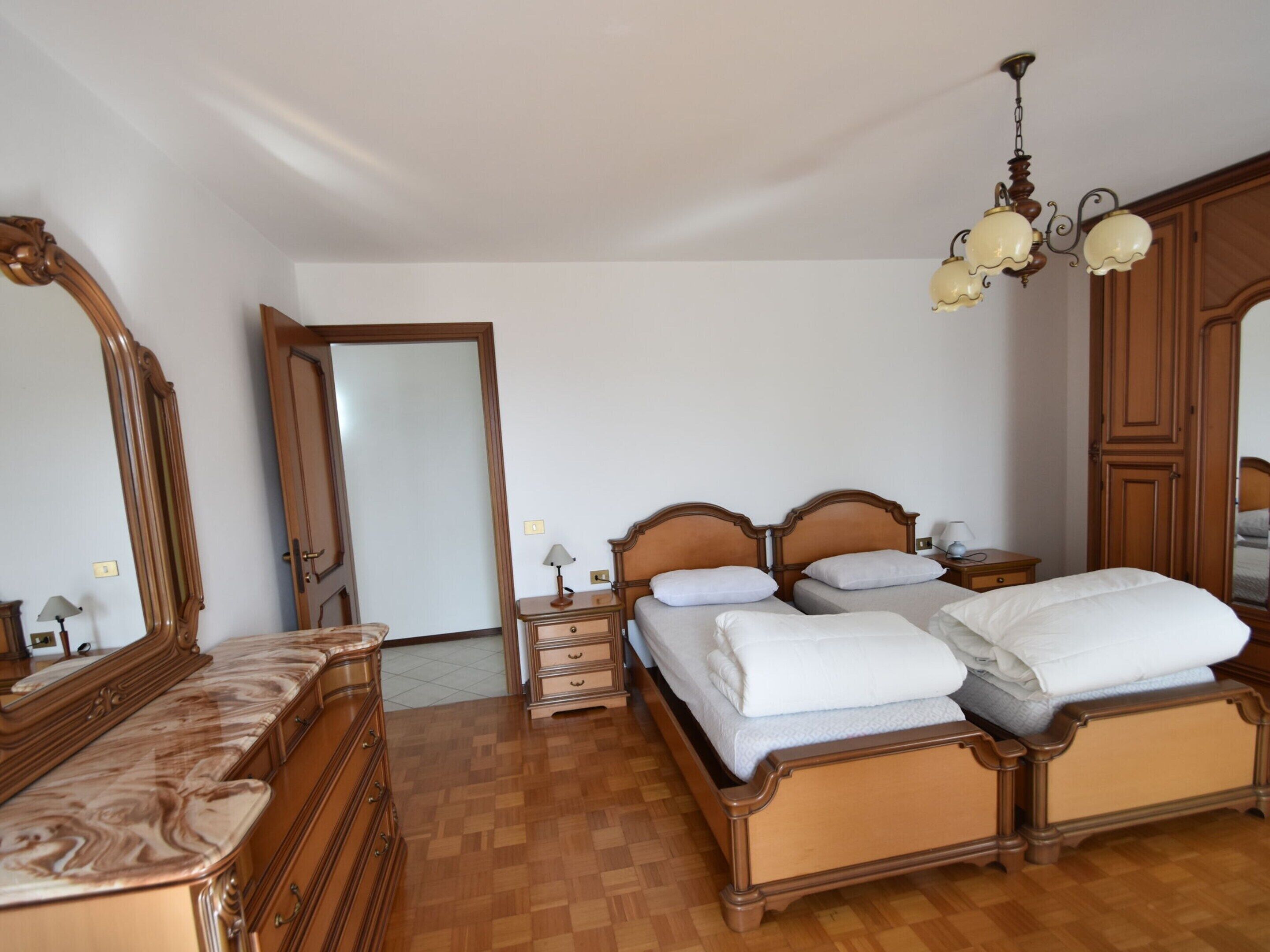 Une chambre à coucher avec un lit en bois, une commode, un miroir et un lustre.