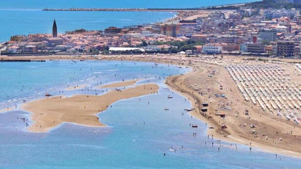 A coastal cityscape with a wide beach, clear blue waters, and a prominent tower. - Belvilla by OYO Inviting Apartment With Pool (Caorle)
