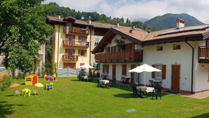 A two-story building with a patio area, outdoor seating, and a view of mountains. - Apartment 4 - attic second floor (Tiarno di Sopra)