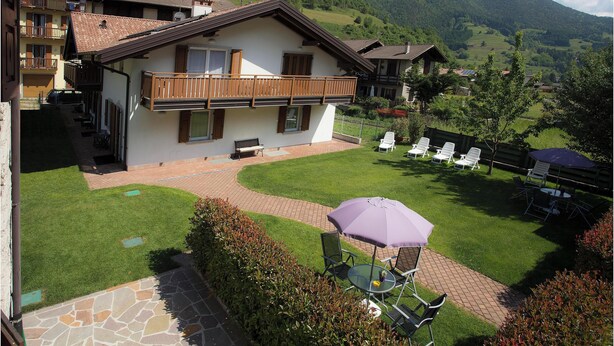 A two-story house with a balcony, a patio with outdoor furniture, and a view of a mountainous landscape. - Apartment 4 - attic second floor (Tiarno di Sopra)